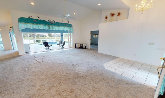 unfurnished living room with light carpet, ceiling fan with notable chandelier, and high vaulted ceiling