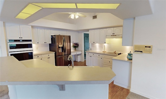 kitchen featuring white double oven, ceiling fan, stainless steel fridge, decorative backsplash, and light hardwood / wood-style floors