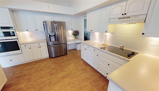 kitchen with tasteful backsplash, white cabinetry, light hardwood / wood-style flooring, and appliances with stainless steel finishes