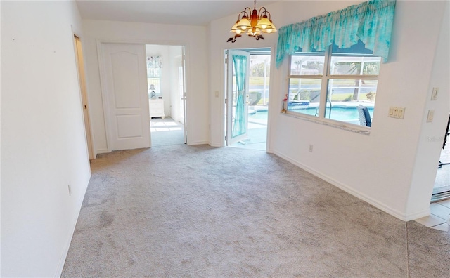 unfurnished room with light carpet and a chandelier