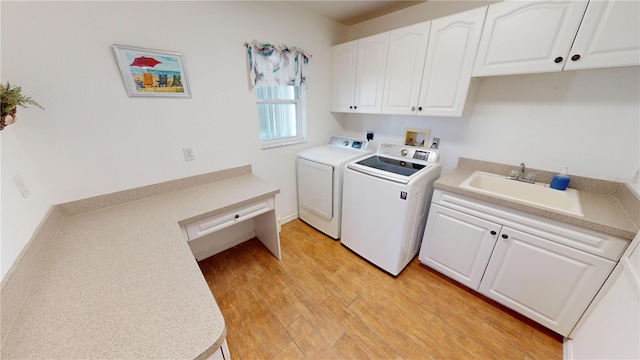 laundry area featuring cabinets, sink, washer and dryer, and light wood-type flooring