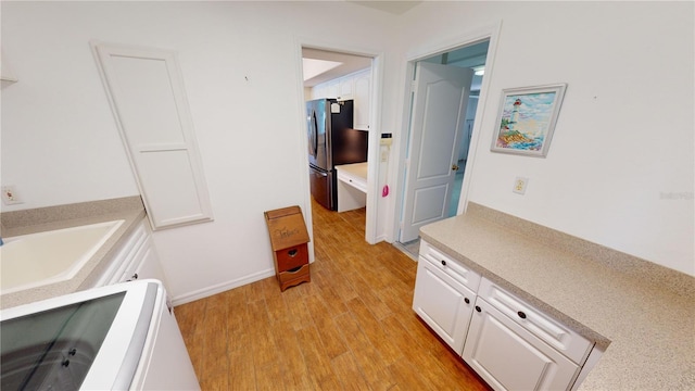 corridor featuring light wood-type flooring and sink