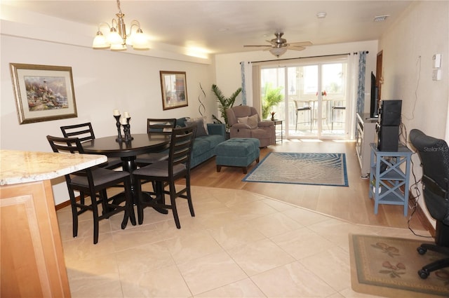 dining space with ceiling fan with notable chandelier and light hardwood / wood-style floors