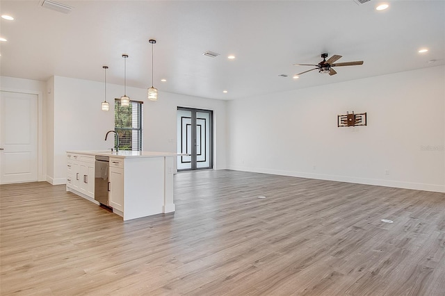 kitchen featuring white cabinets, pendant lighting, light hardwood / wood-style floors, and stainless steel dishwasher