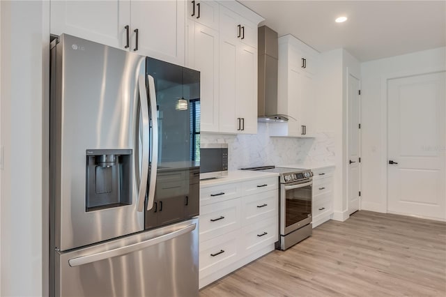 kitchen with white cabinetry, wall chimney exhaust hood, light hardwood / wood-style flooring, decorative backsplash, and appliances with stainless steel finishes