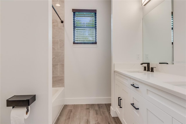 bathroom with hardwood / wood-style floors, vanity, and tiled shower / bath combo