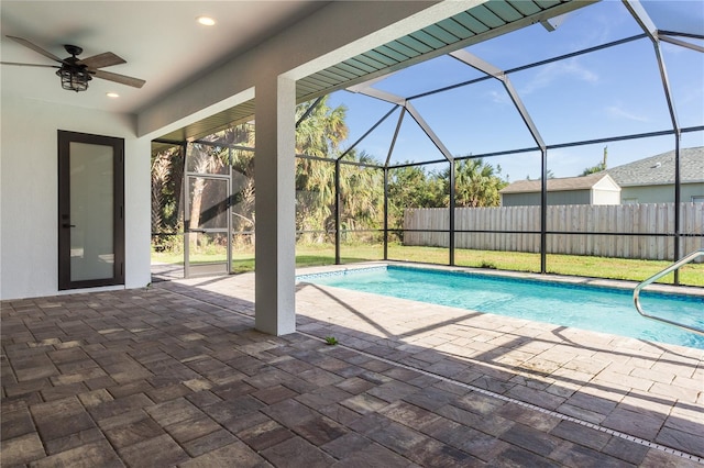 view of pool featuring a patio, glass enclosure, and ceiling fan