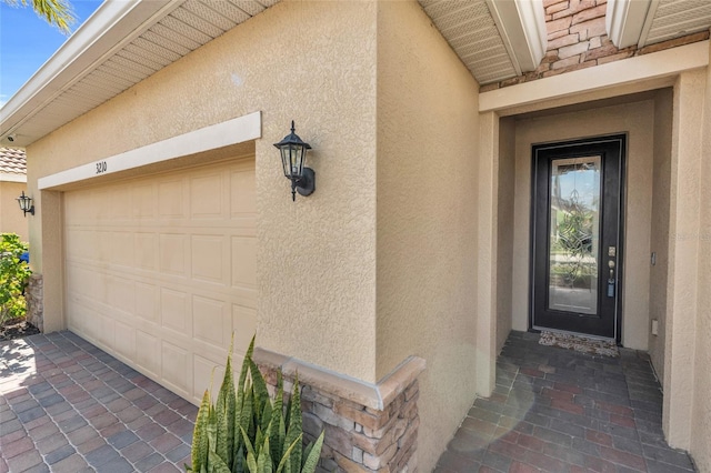 property entrance featuring an attached garage and stucco siding