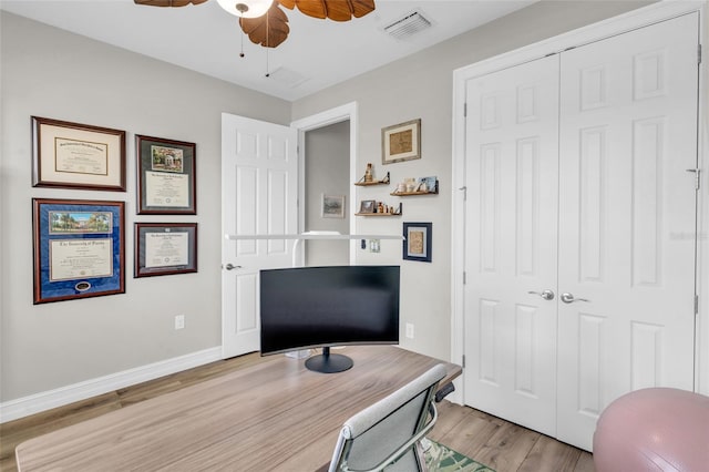 office area with baseboards, a ceiling fan, visible vents, and light wood-style floors