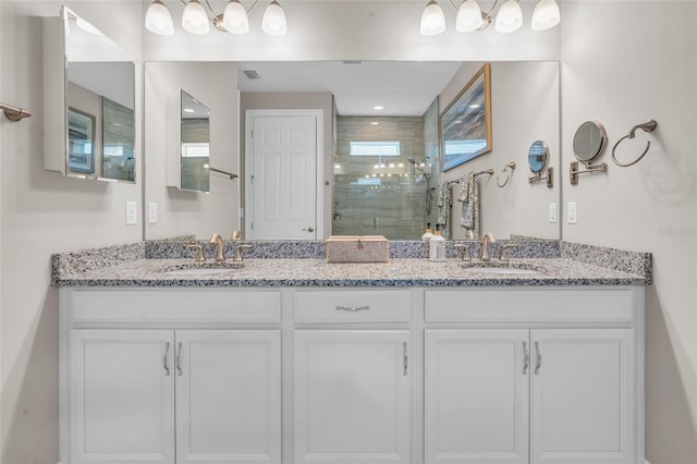 full bath with visible vents, a sink, a tile shower, and double vanity