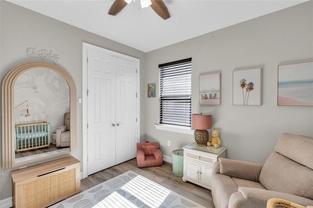 living area featuring light wood-type flooring, a ceiling fan, and baseboards