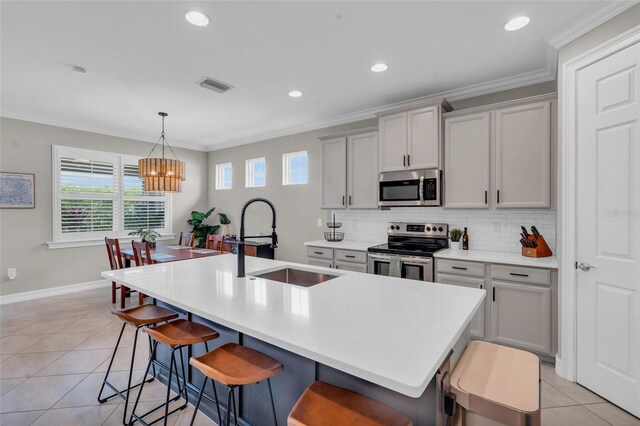 kitchen featuring tasteful backsplash, visible vents, appliances with stainless steel finishes, a kitchen bar, and a sink