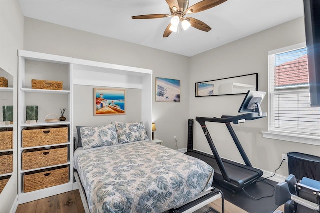 bedroom featuring ceiling fan, baseboards, and wood finished floors