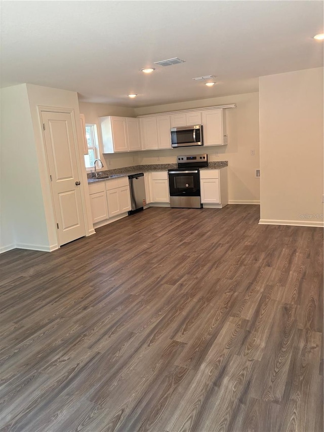 kitchen featuring appliances with stainless steel finishes, dark hardwood / wood-style flooring, sink, and white cabinets