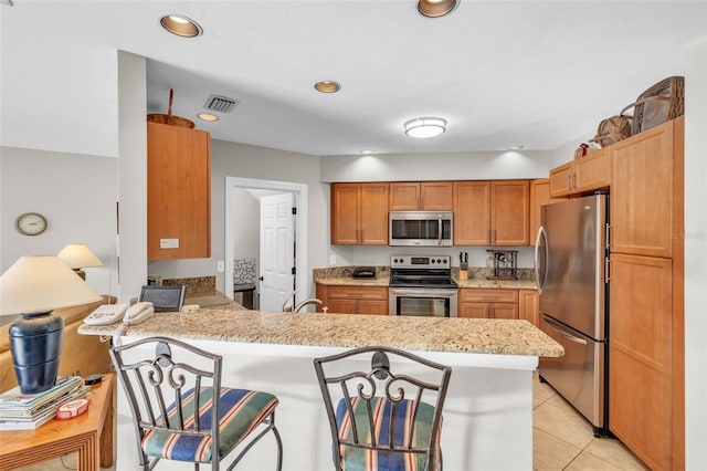 kitchen with kitchen peninsula, light stone counters, stainless steel appliances, sink, and light tile patterned floors