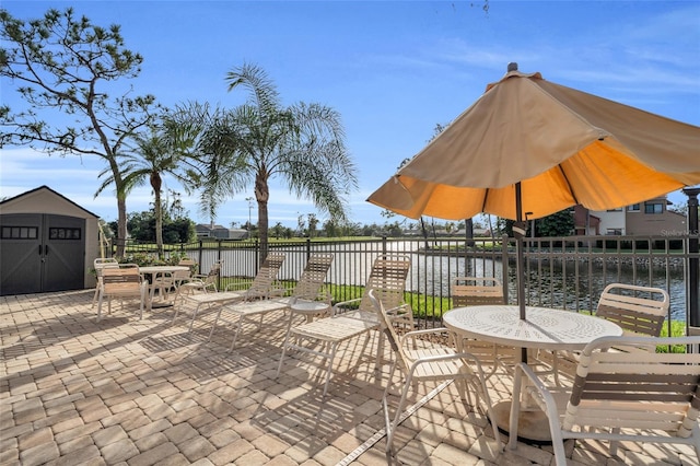 view of patio with a water view and a storage unit