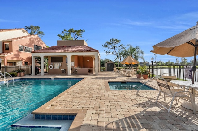 view of swimming pool featuring an outdoor kitchen, a patio area, and a shed