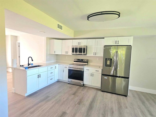 kitchen featuring appliances with stainless steel finishes, light hardwood / wood-style floors, white cabinetry, and sink