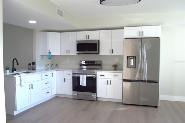 kitchen featuring white cabinetry, sink, stainless steel appliances, and light hardwood / wood-style floors