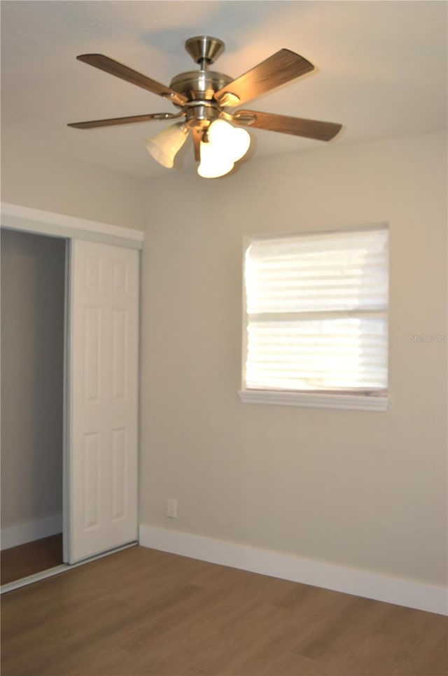 unfurnished bedroom featuring ceiling fan, wood-type flooring, and a closet