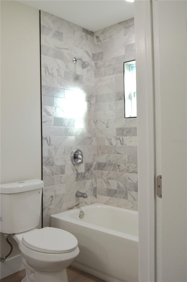 bathroom featuring tiled shower / bath combo and toilet