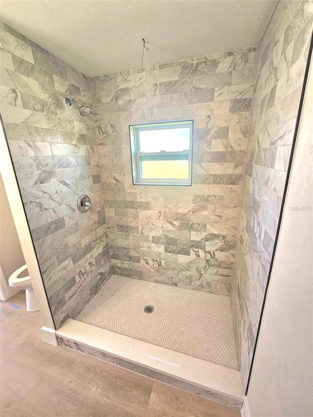 bathroom featuring tiled shower and toilet