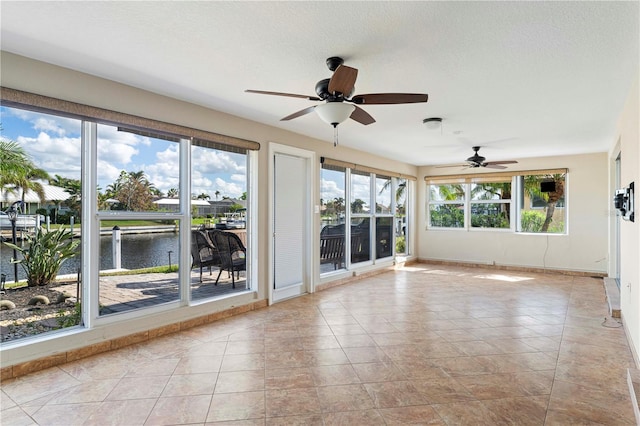 interior space featuring ceiling fan, plenty of natural light, and a water view