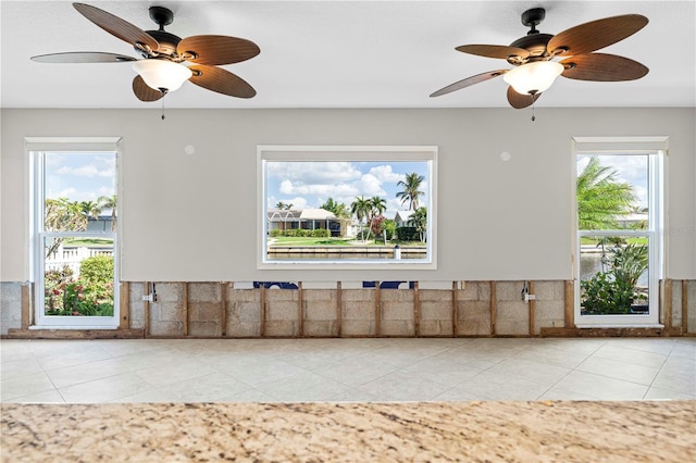 unfurnished living room featuring ceiling fan and light tile patterned floors