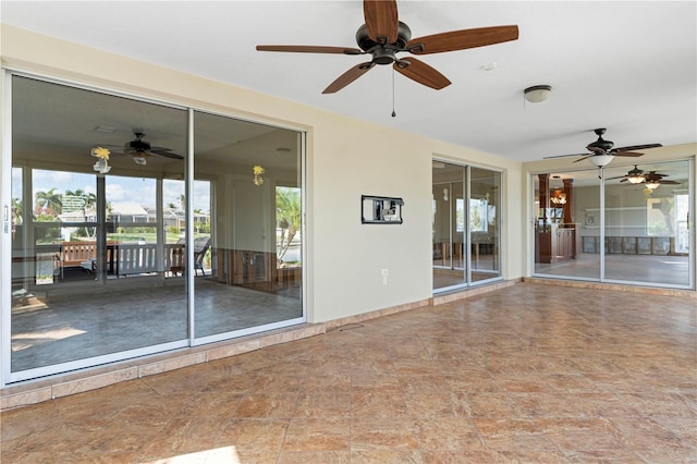 unfurnished sunroom featuring ceiling fan and a healthy amount of sunlight