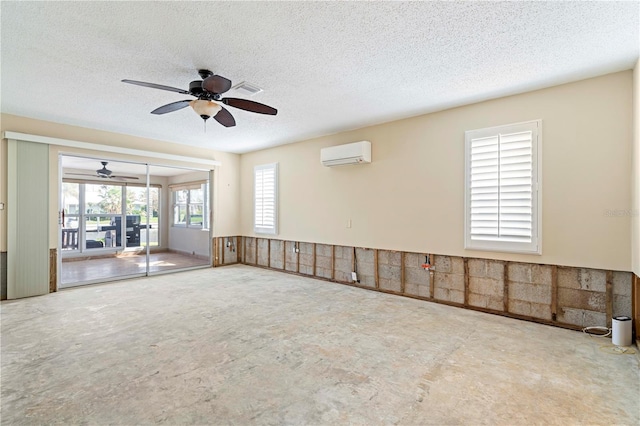 unfurnished room featuring a wall unit AC, ceiling fan, and a textured ceiling