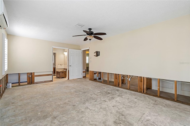 unfurnished room featuring a wall mounted AC, ceiling fan, and a textured ceiling