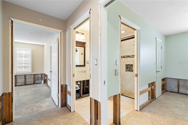 corridor with light tile patterned floors and a textured ceiling