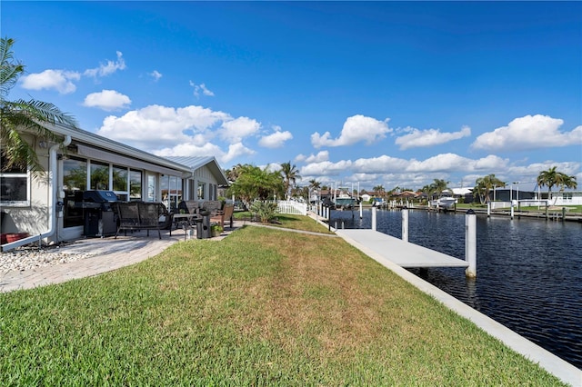 dock area featuring a lawn, a water view, and a patio