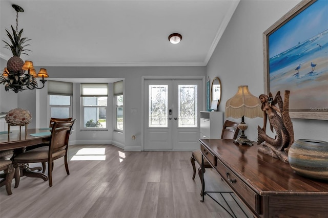 foyer entrance featuring a chandelier, crown molding, french doors, and light hardwood / wood-style floors