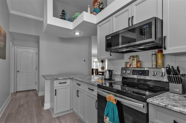 kitchen featuring white cabinets, light wood-type flooring, stainless steel appliances, and light stone counters