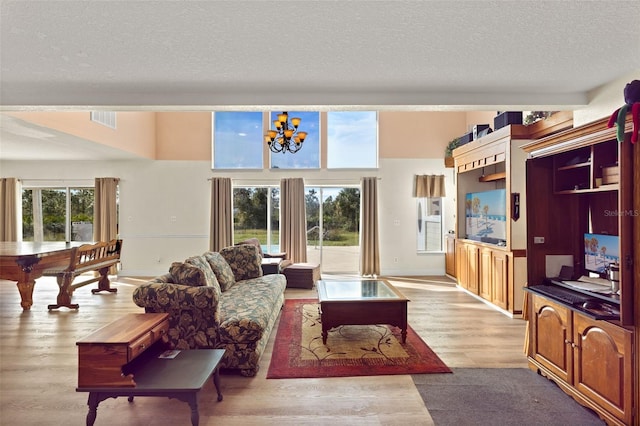 living room featuring plenty of natural light, a textured ceiling, and light wood-type flooring