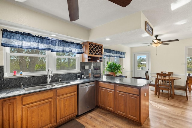 kitchen with stainless steel dishwasher, sink, light wood-type flooring, and kitchen peninsula