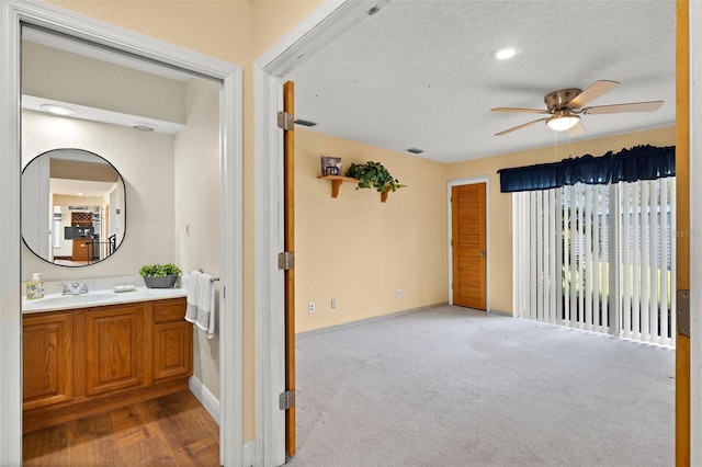 interior space featuring ceiling fan, vanity, and a textured ceiling