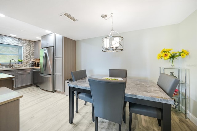 dining area featuring a chandelier, sink, and light hardwood / wood-style floors