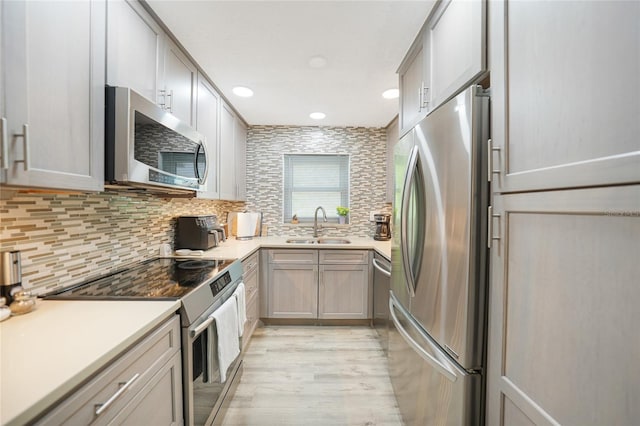 kitchen with decorative backsplash, gray cabinetry, stainless steel appliances, sink, and light hardwood / wood-style flooring