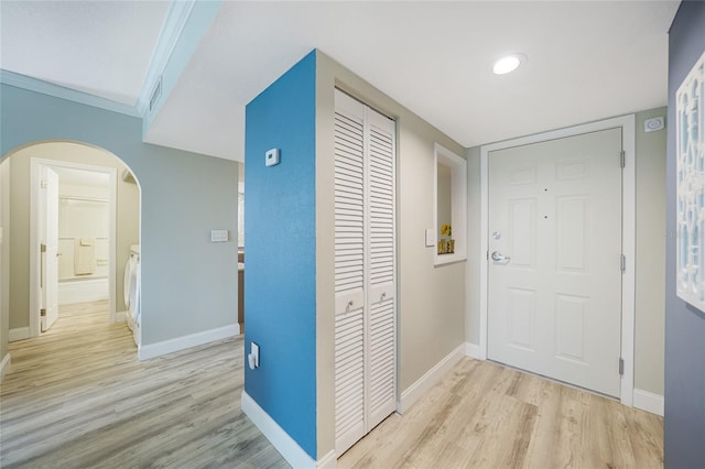 corridor with light hardwood / wood-style flooring and ornamental molding