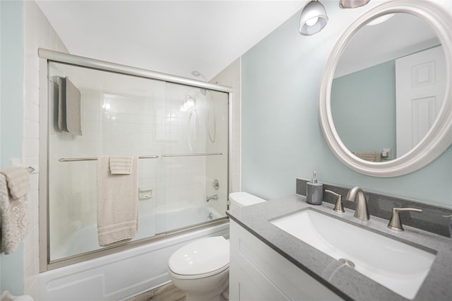 full bathroom with vanity, bath / shower combo with glass door, and toilet