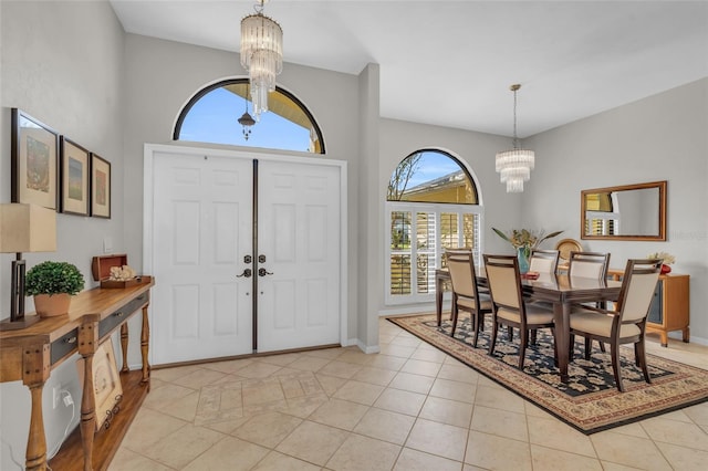 entryway featuring light tile patterned floors, a chandelier, and a high ceiling