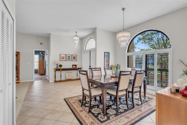 tiled dining space featuring plenty of natural light, a towering ceiling, and a chandelier