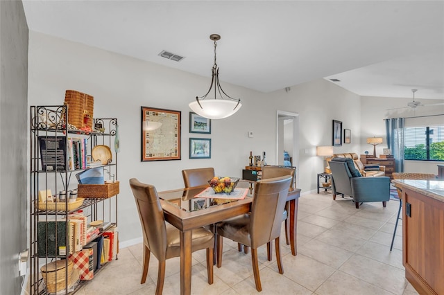 dining area featuring ceiling fan, light tile patterned floors, and vaulted ceiling