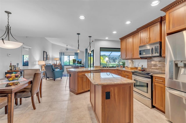 kitchen featuring appliances with stainless steel finishes, vaulted ceiling, decorative light fixtures, and a kitchen island