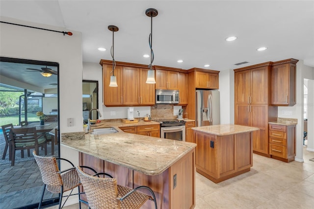 kitchen featuring kitchen peninsula, ceiling fan, decorative light fixtures, and appliances with stainless steel finishes