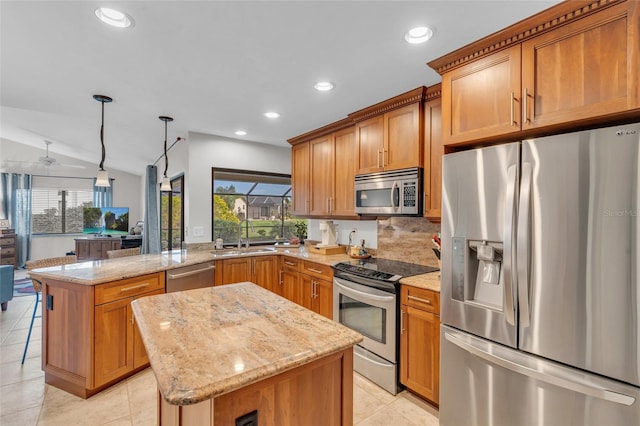 kitchen with decorative light fixtures, a kitchen island, lofted ceiling, and appliances with stainless steel finishes