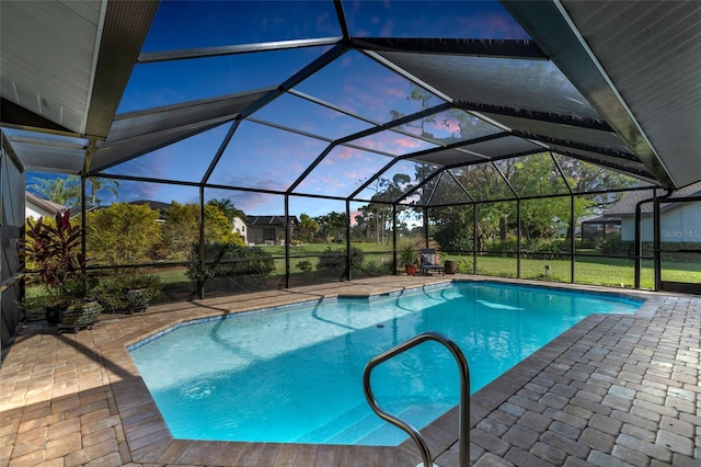 pool at dusk with glass enclosure, a yard, and a patio