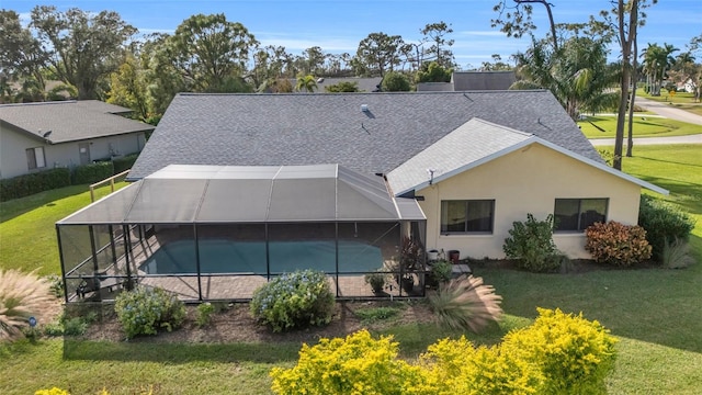 rear view of property featuring a lawn and glass enclosure